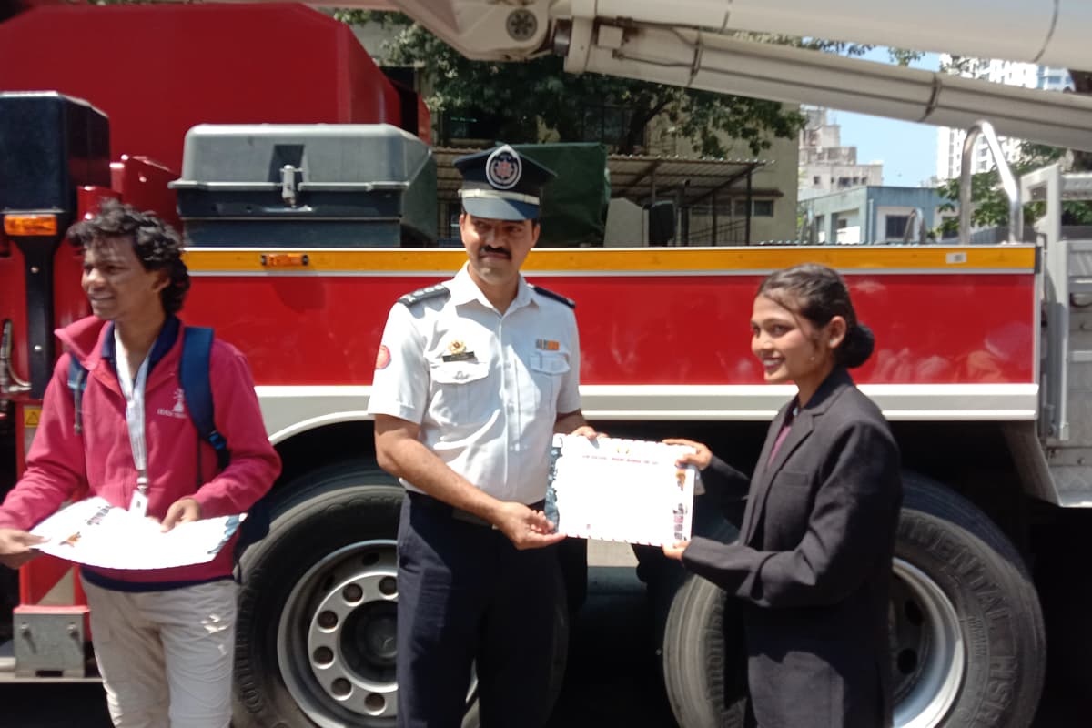 A fire officer handing a letter to a Centuria student in front of a fire tender